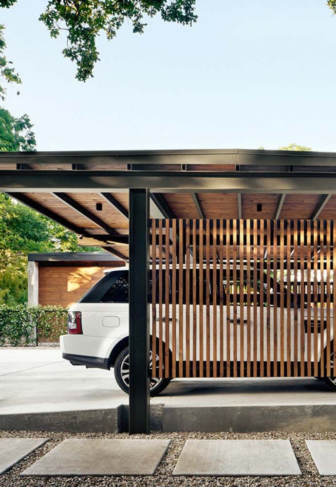 a car is parked in front of a wooden structure with vertical slats on it