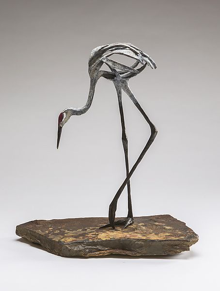 a metal sculpture of a flamingo standing on a rock