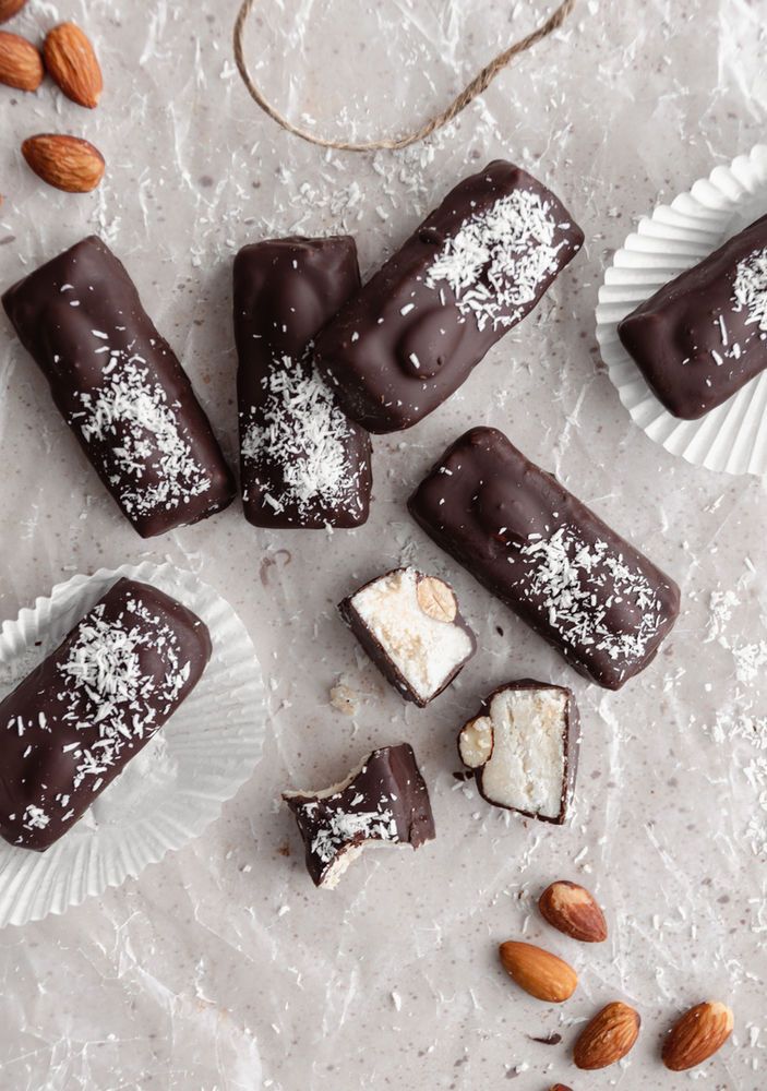 several pieces of chocolate with almonds and nuts on the table next to them,