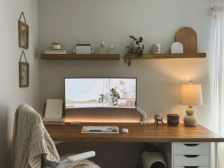 a desk with a computer monitor, lamp and pictures on the wall above it in a home office