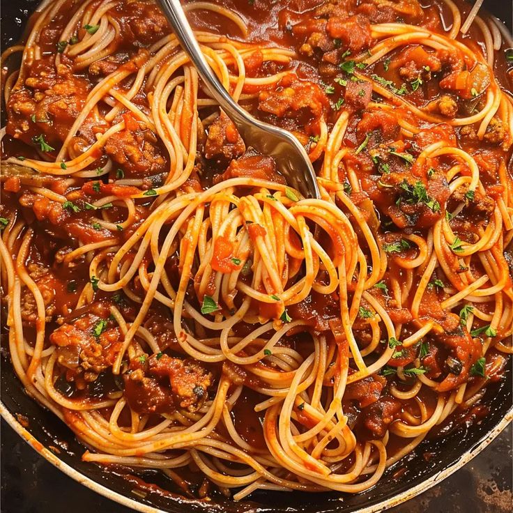 a skillet filled with spaghetti and meat sauce