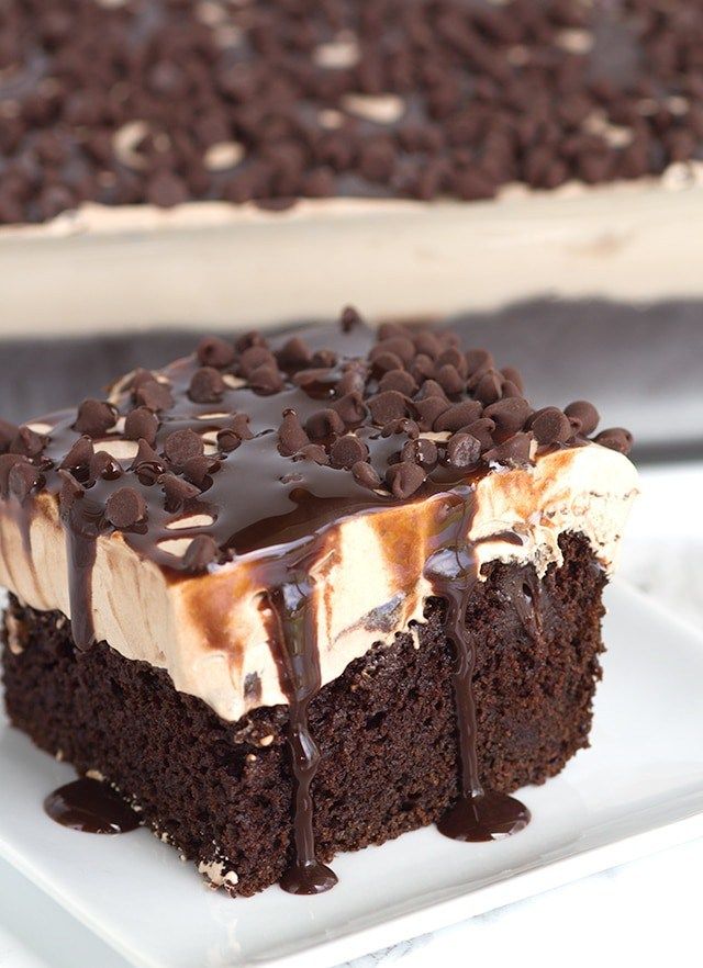 a piece of chocolate cake with ice cream and chocolate chips on top, sitting on a white plate