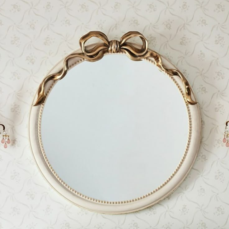 a round mirror sitting on top of a wall next to two small clips of hair