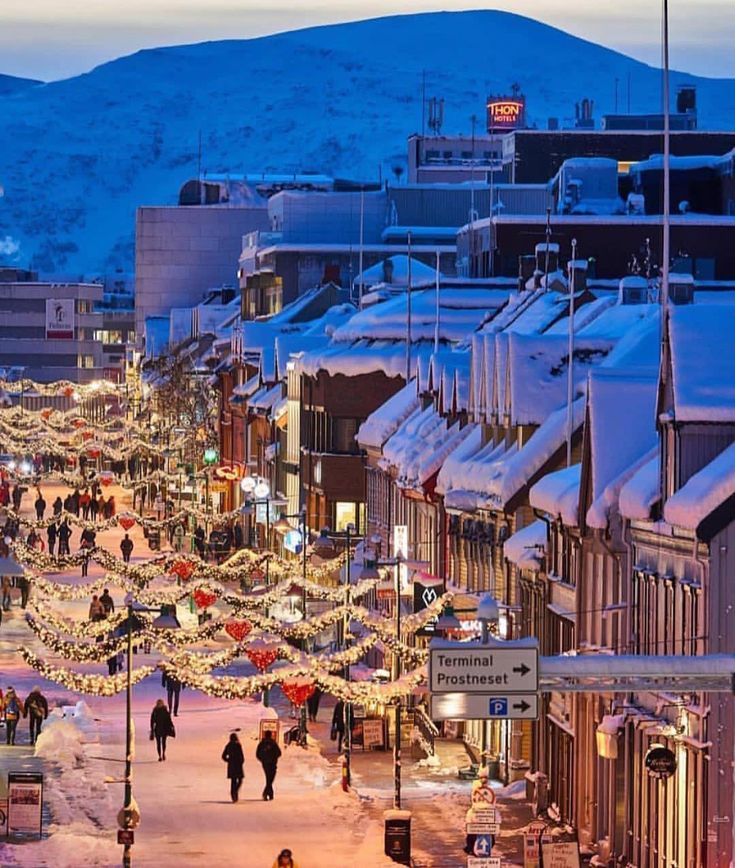 people are walking down the street at christmas time in this town with snow on the ground