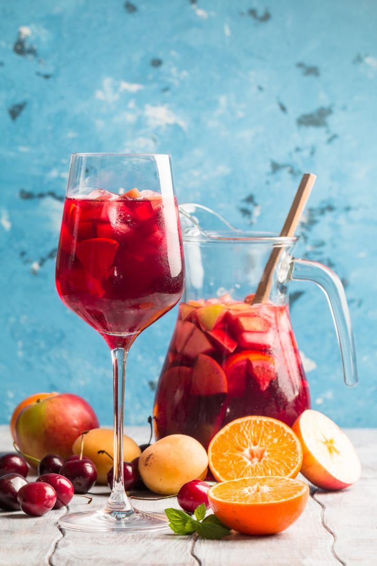 a pitcher and glass filled with liquid next to fruit