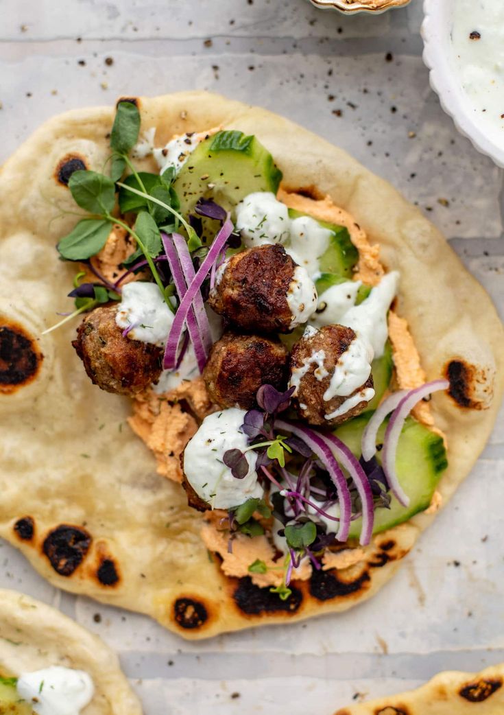 two pita breads with meatballs and veggies on them