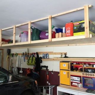 a car is parked in front of a garage shelving unit with various items on it