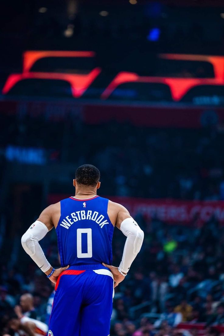 a man standing on top of a basketball court with his back to the camera while wearing a blue uniform