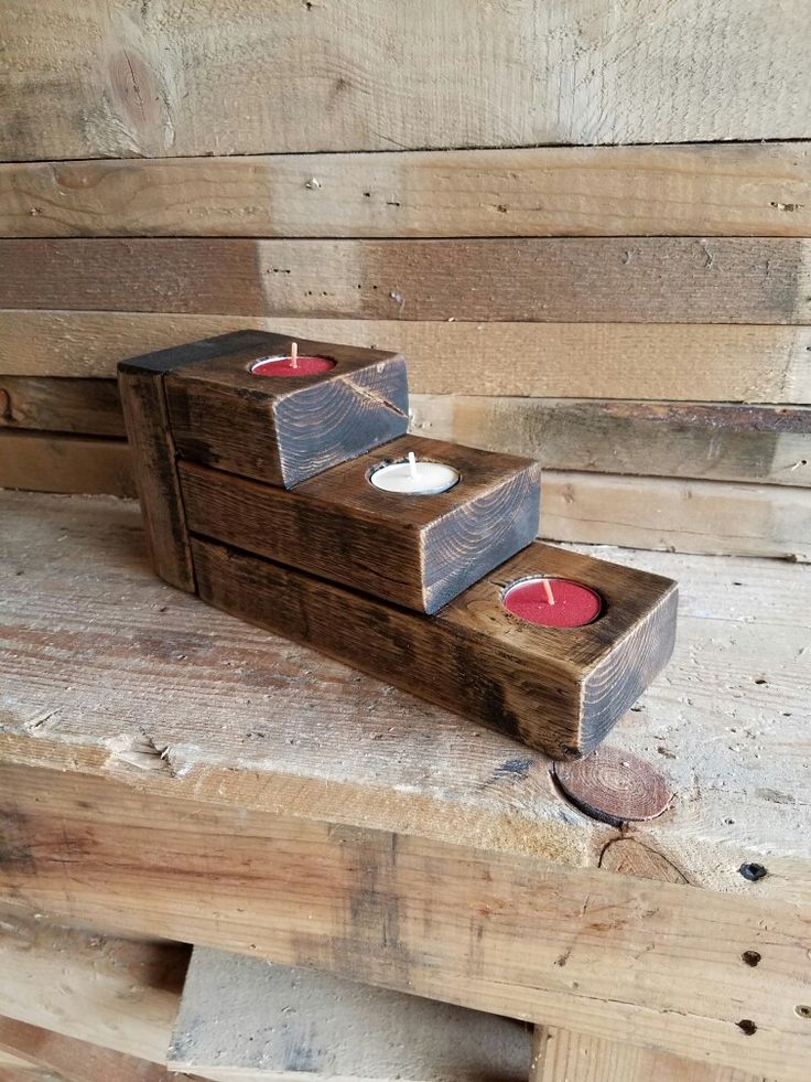 two wooden boxes with candles in them on top of some wood planks next to each other