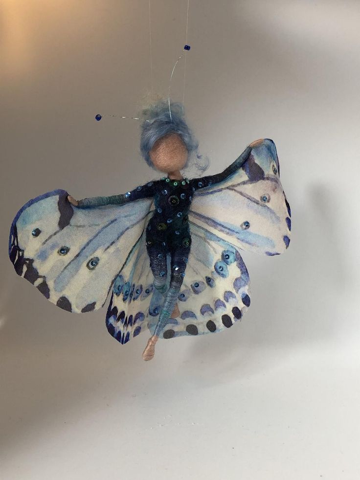 a blue and black butterfly ornament hanging from a string on a white wall