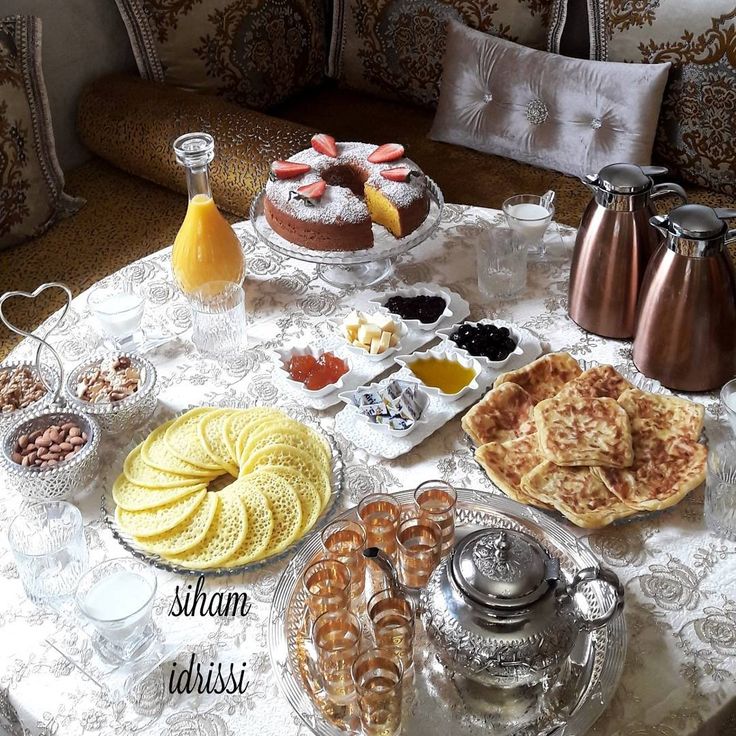 a table topped with lots of food on top of a white cloth covered tablecloth