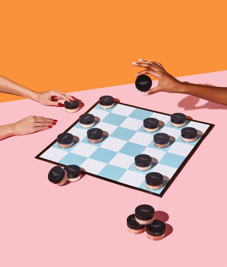 two women are playing checkers on a pink and orange background with black cookies in the foreground