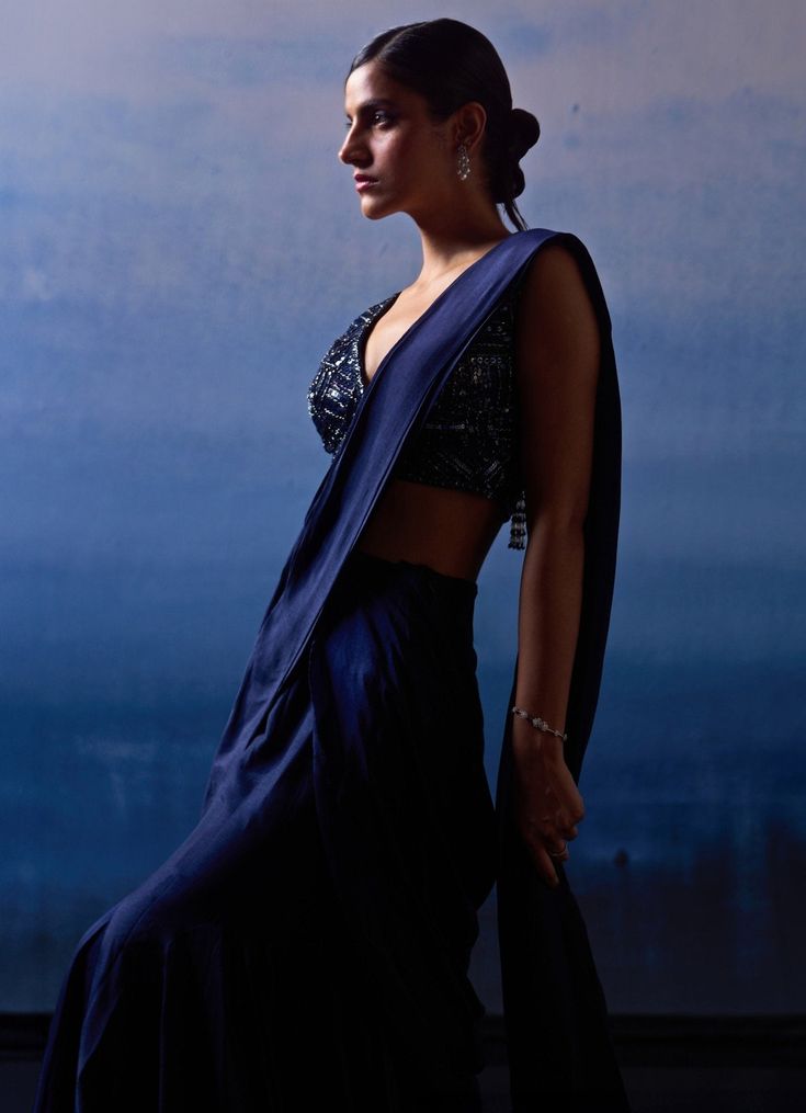 Elevate your evening wear with a stunning Midnight Blue Silk Drape Saree. Crafted from luxurious silk, the deep, rich hue of the saree contrasts elegantly with the intricate detailing on the blouse. The beautifully embroidered blouse is adorned with tonal sequins, crystals, and bugle beads, adding a touch of sparkle and sophistication. Ideal for Mehendi, Sangeet nights or wedding guest attire. Composition : Saree and Blouse - Silk Care: Dry Clean Only and Vacuum Storage This product can be customized for sleeves, length and colour Delivery : 6-8 weeks as the product is hand crafted. Check Size Guide or choose MySize for free customisation (All Sizes above XL can be made at 15% additional cost) For more information and sizes please contact fabiliciousfashion@gmail.com or visit our Copenhage Traditional Drape Satin Choli, Luxury Blue Pre-draped Saree For Evening, Festive Satin Pre-draped Saree In Traditional Shape, Pre-draped Silk Saree With Pallu For Party, Elegant Art Silk Saree For Evening, Traditional Style Satin Blouse Piece For Evening, Traditional Satin Blouse Piece For Evening, Silk Evening Saree For Diwali, Traditional Blue Pre-draped Saree For Evening