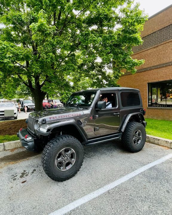 a black jeep parked in front of a building on the side of a road next to a tree