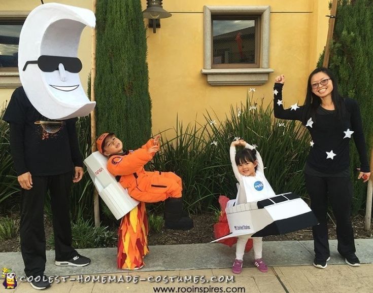 three people in costumes posing for a photo with one holding up a paper bag and the other pointing at something