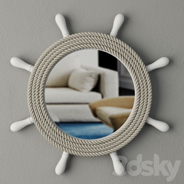 a round mirror with rope on the side and a white couch in the back ground