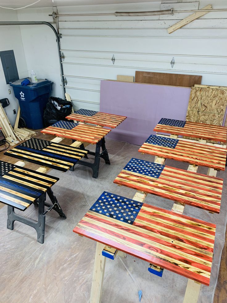 several wooden tables with american flags painted on them in a garage area next to other furniture