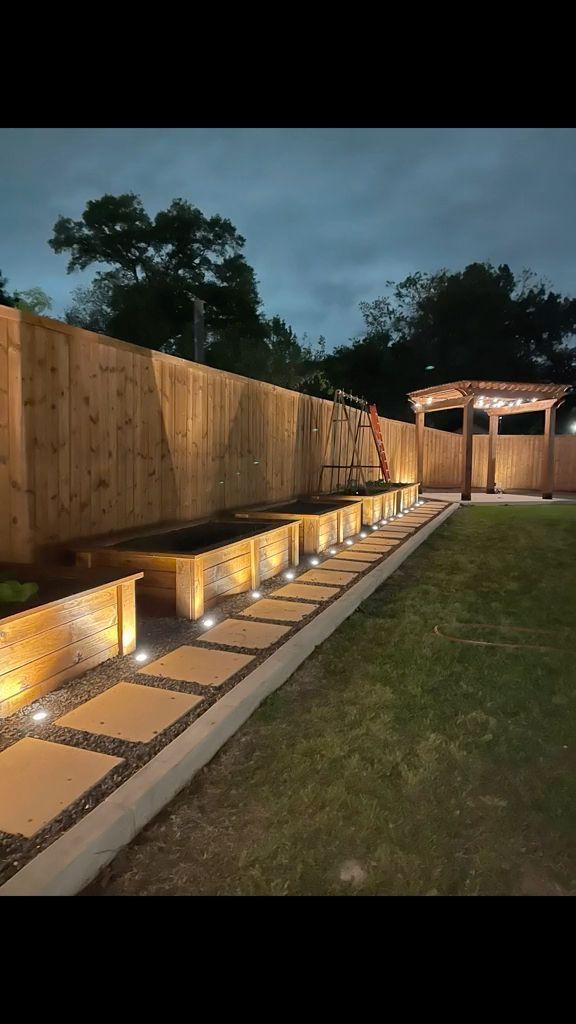 a garden with lights on the side of it and some grass in front of it