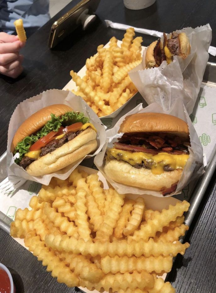 three hamburgers and fries on a tray with ketchup