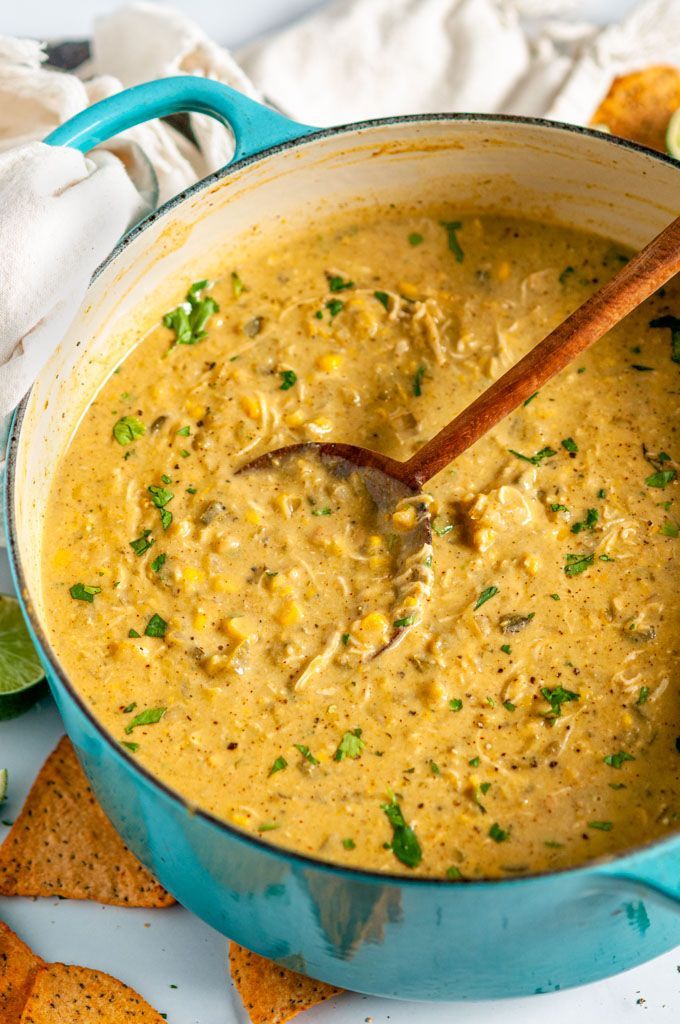 a blue pot filled with soup next to tortilla chips and lime wedges