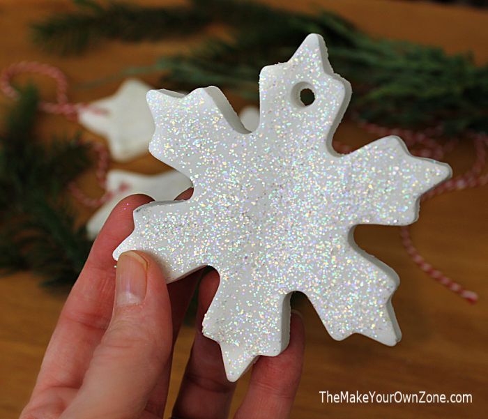 someone is holding a snowflake ornament in their hand on a table