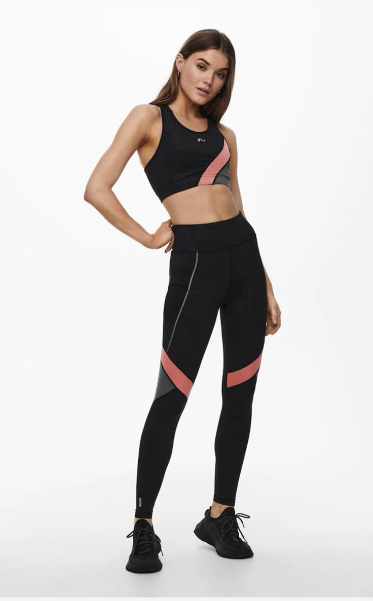 a woman in black sports bra top and leggings standing with her hands on her hips