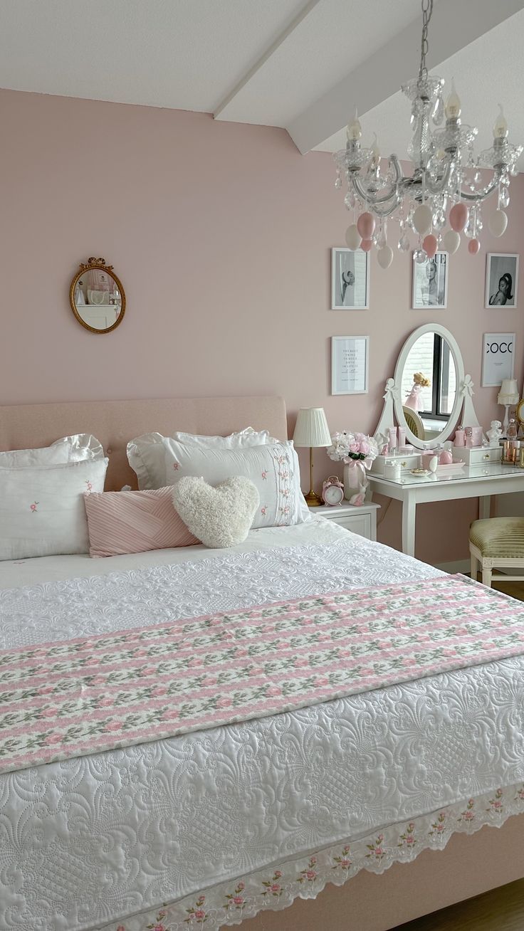 a bedroom with pink walls, white bedding and a chandelier hanging from the ceiling