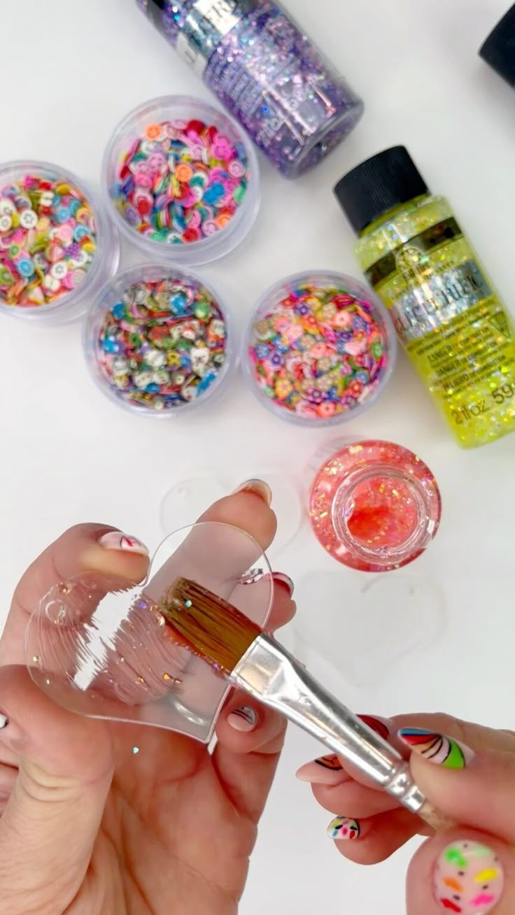 a woman is holding a small glass with sprinkles on it and some scissors in front of her