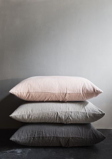 three pillows stacked on top of each other in front of a gray wall and floor