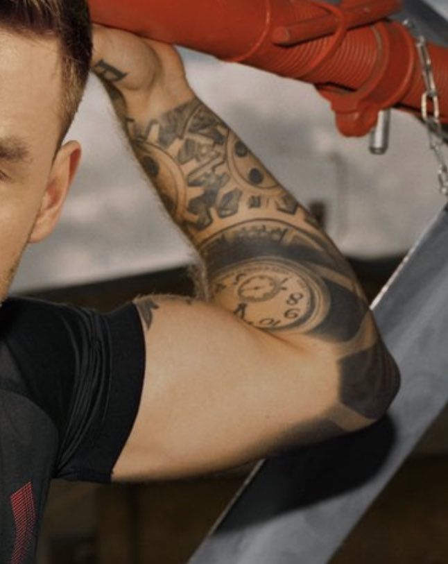 a man with tattoos on his arm and arms is holding a red glove over his head