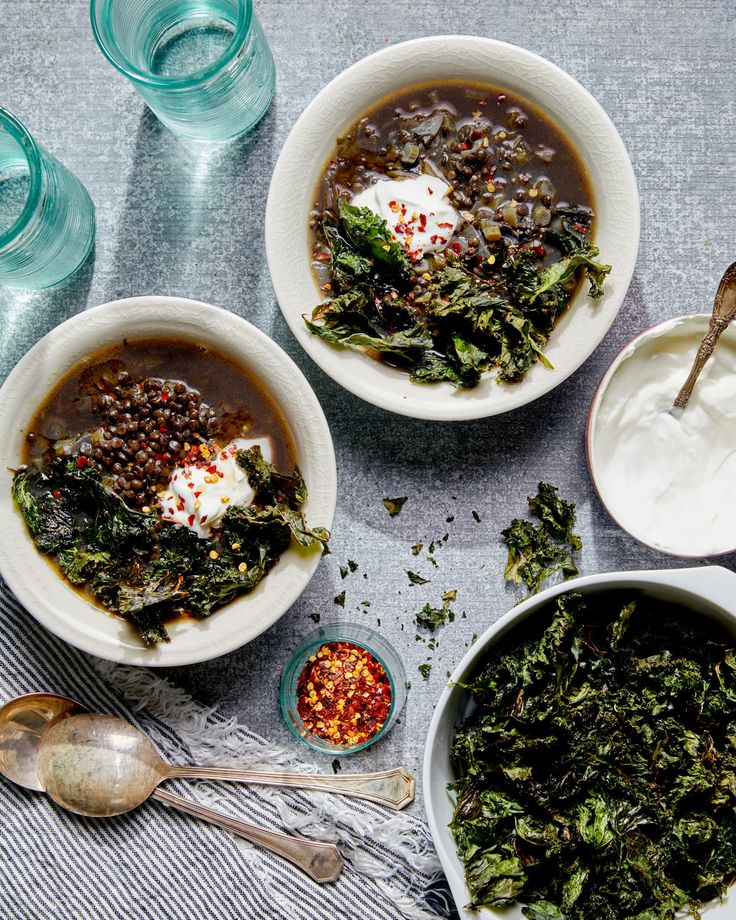 three bowls filled with different types of food next to spoons and cups on a table