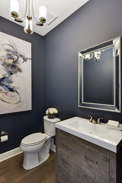 a white toilet sitting next to a bathroom sink under a large painting on the wall