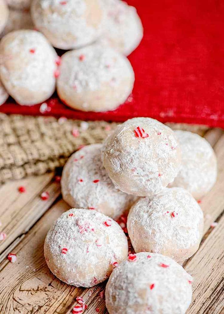 white powdered sugar cookies with red and white sprinkles on a wooden table