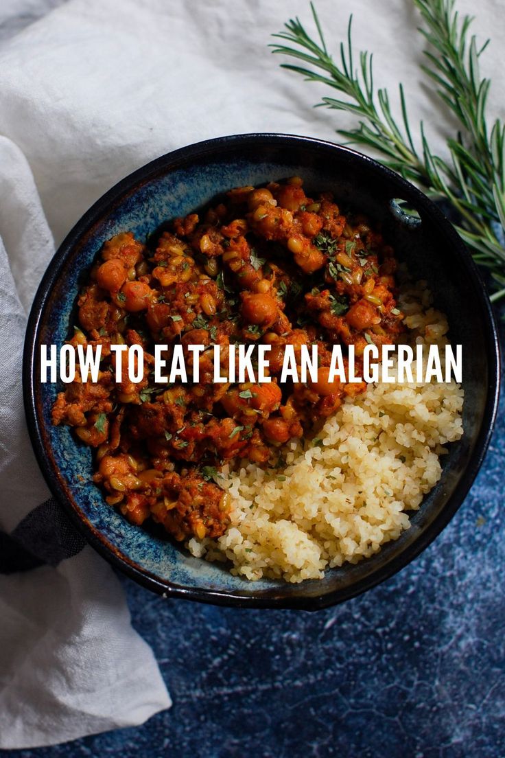 a blue bowl filled with rice and meat next to a sprig of rosemary