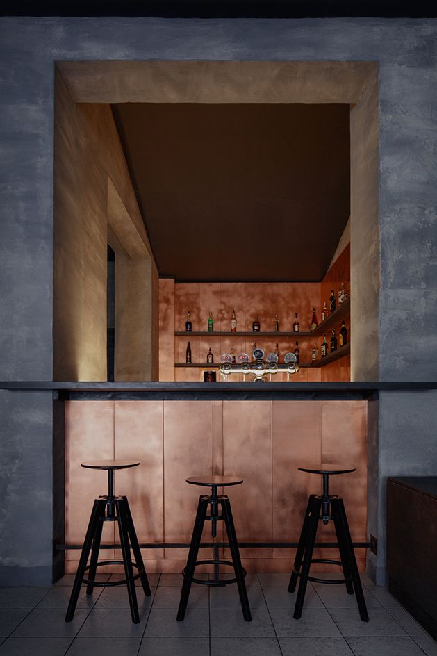 two stools in front of a bar with bottles on the shelves