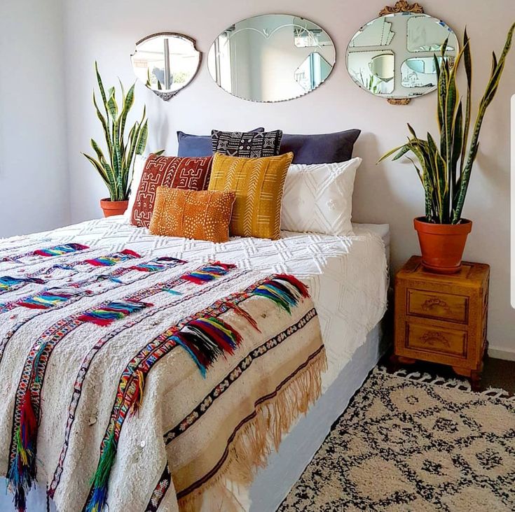 a bed sitting in a bedroom next to two planters and mirrors on the wall