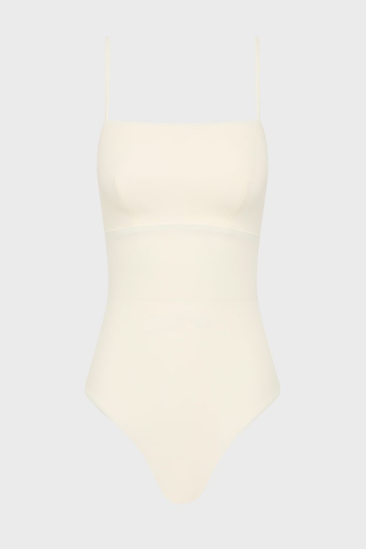 The Aerin One Piece in Pearl is an elegant, contemporary swimsuit with a flattering square neckline. With a bust panel, hidden under-bust support and removable cups, Aerin is supremely flattering to a woman's figure. Cut from our technically advanced Sculpteur® fabric with 3-D stretch, Aerin will support the bust and streamline the body. A chic swimsuit that idea for larger busts, suiting cup sizes B to DD. Luxury fabric sustainably made in Italy. Shaping Swimwear With Built-in Bra For Summer, Summer Swimwear With Built-in Bra And Straight Neckline, White Square Neck Swimwear For Swimming, Elegant Swimwear With Lined Body And Minimal Stretch, White Square Neck Swimwear For Beach, Elegant Summer Bodysuit With Minimal Stretch, Summer Shapewear For Swimming, Elegant Bodysuit With Minimal Stretch And Lined Body, Elegant Bodysuit With Minimal Stretch