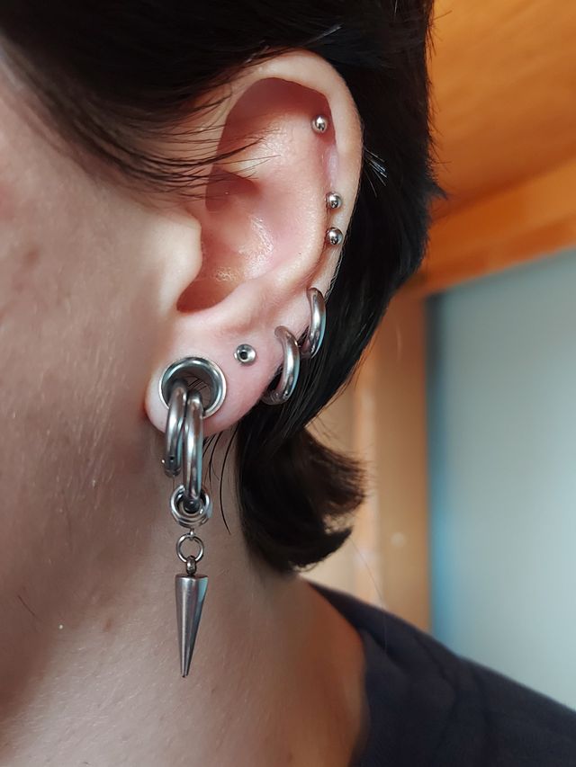 a close up of a person wearing ear piercings with spikes and chains attached to them