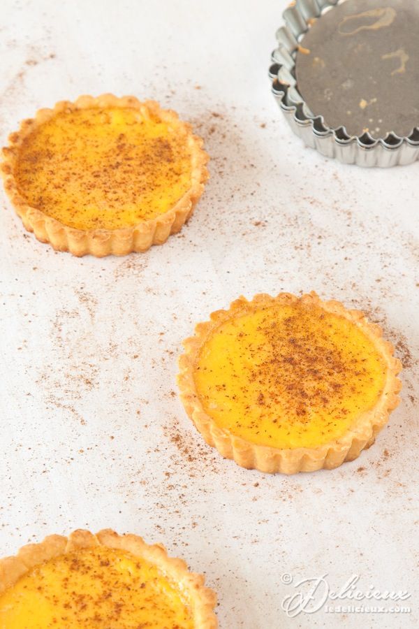 three small pies sitting on top of a white counter next to a metal pan