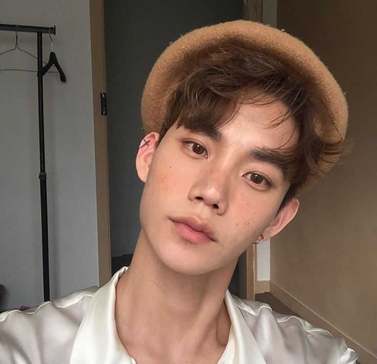 a young man wearing a brown hat looking at the camera