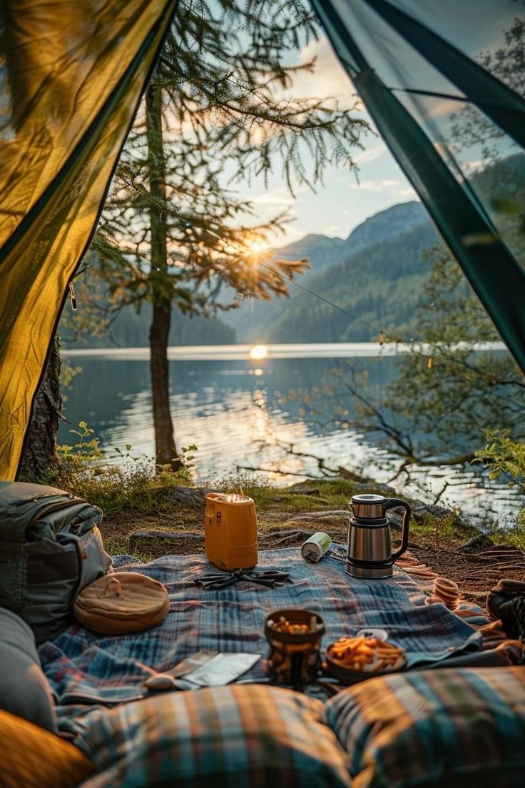 an open tent with food and coffee on the ground next to it, overlooking a body of water