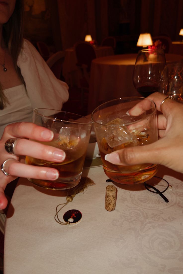 two people are toasting with drinks at a table