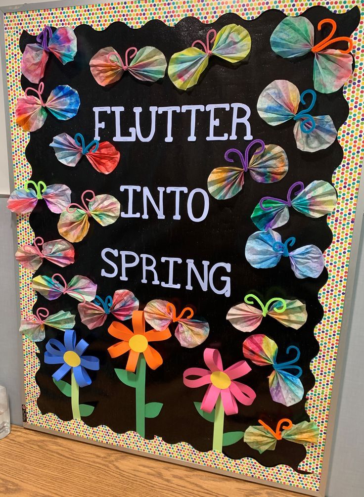 a bulletin board with flowers and butterflies on it that says, flutter into spring in front of a blackboard