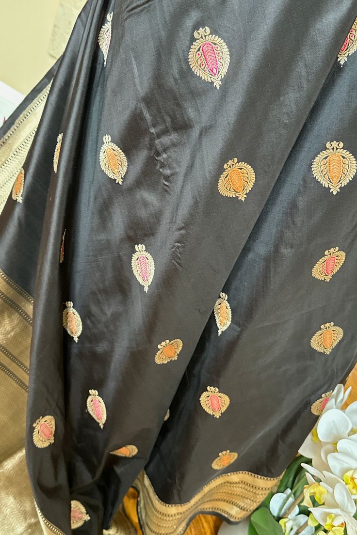 This exquisite handwoven banarasi silk saree in black with minakari anar buttis is nothing but enchanting. Beautiful border with tine beaded lines and traditional motifs accentuates the saree very well. The grand elaborate zari woven pallu is nothing but regal. Approximate Length 6.5 mtrs (inclusive of blouse length)Height - 46 - 52" Saree comes with fall, picot and tassels done. Blouse piece is cut. Approximate weight - 1.3 lbs Kindly Note : The colors you see on your device may vary due to the color reproduction, brightness and resolution of individual devices. If you'd like more clarity before your purchase, please contact our support team. Traditional Black Chanderi Saree, Black Art Silk Saree With Zari Work, Black Art Silk Saree With Pallu, Black Art Silk Saree With Traditional Drape, Black Chanderi Traditional Wear, Black Art Silk Saree For Diwali, Unstitched Black Art Silk Saree, Black Tussar Silk Dupatta With Traditional Drape, Black Tussar Silk Traditional Wear With Zari Work