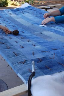 two people are laying on a blue tarp and one person is using a pair of scissors