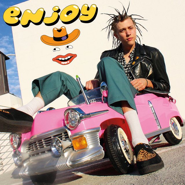 a man sitting on top of a pink car with an emoy sign in the background