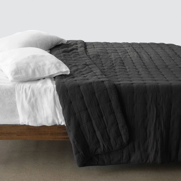 the bed is made with black linens and white pillow cases on top of it