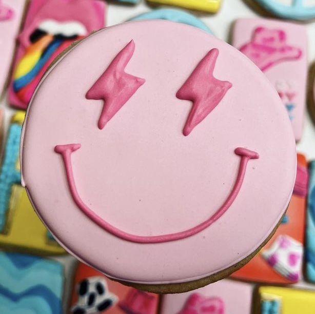 a pink smiley face cookie sitting on top of a table