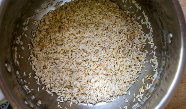 a large metal bowl filled with rice on top of a wooden table