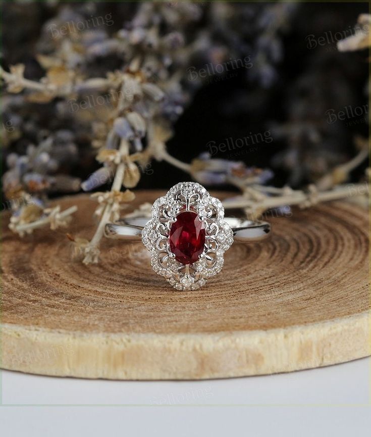 a close up of a ring on a piece of wood with flowers in the background